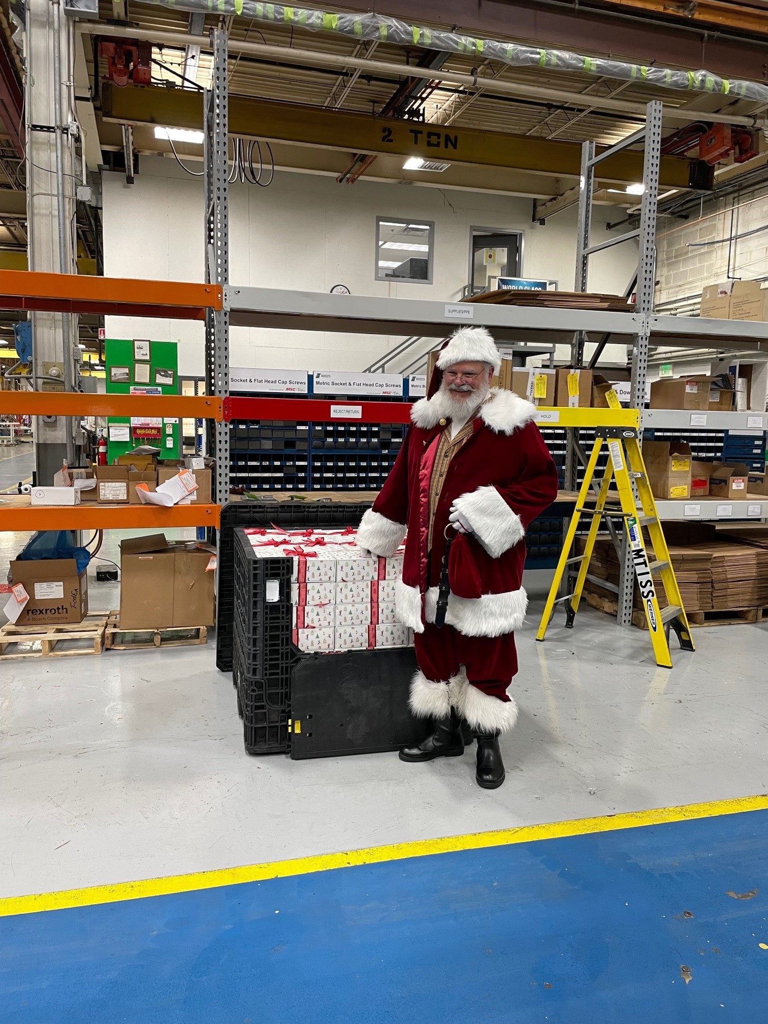 MTI's Ed Shorten poses as Santa in front of a pile of presents